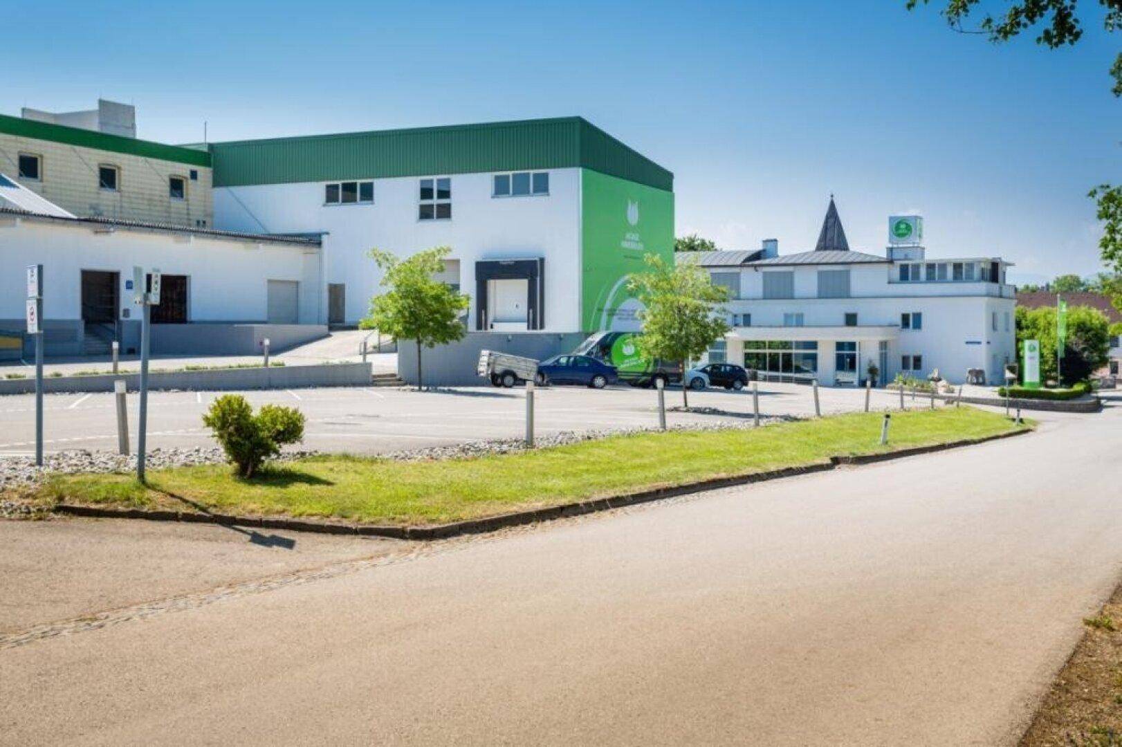 Außenansicht eines modernen Geschäftsgebäudes mit grünen Akzenten und einem geräumigen Parkplatz.