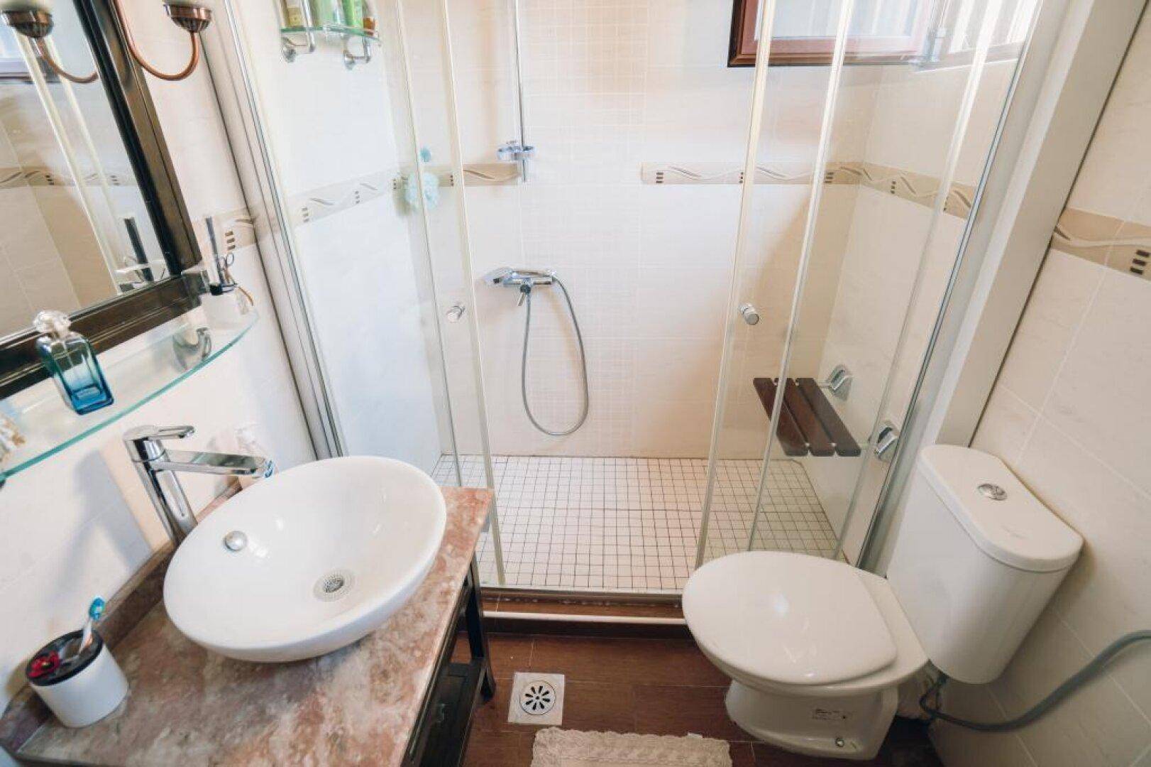 Modernes Badezimmer mit Duschkabine, Aufsatzwaschbecken und Marmorwaschtisch.