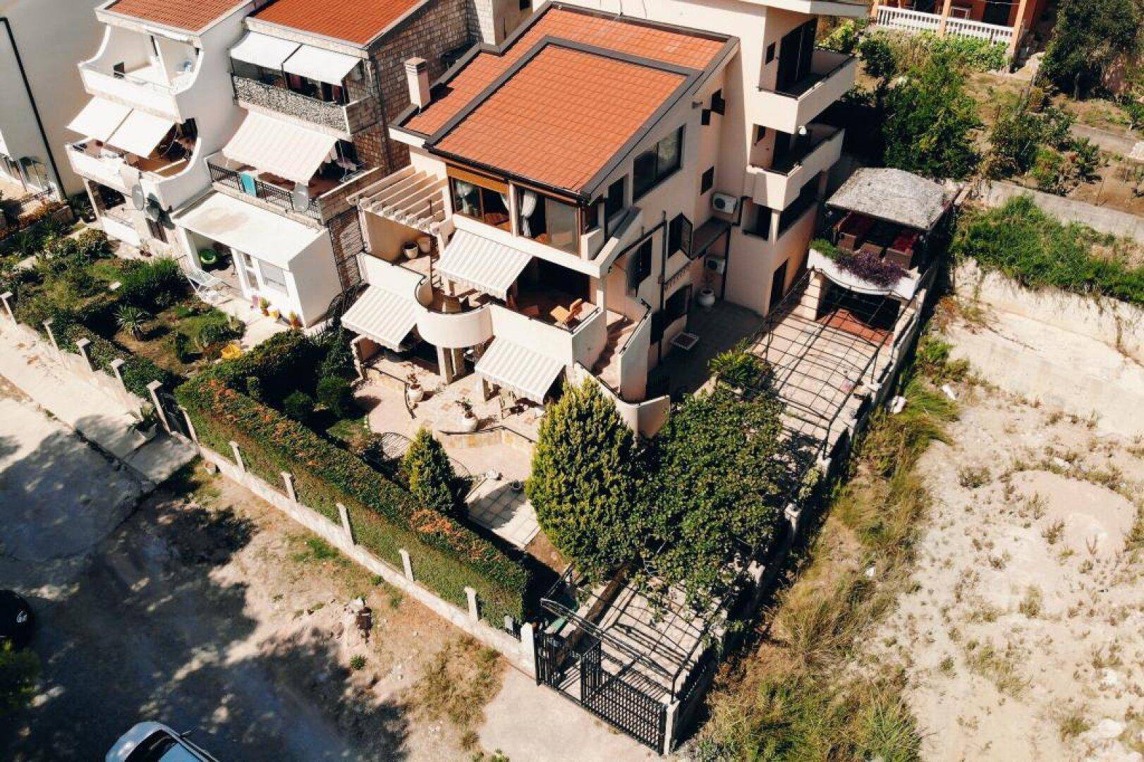 Luftaufnahme eines Hauses mit mehreren Terrassen, einem gepflegten Garten und einer Hecke.
