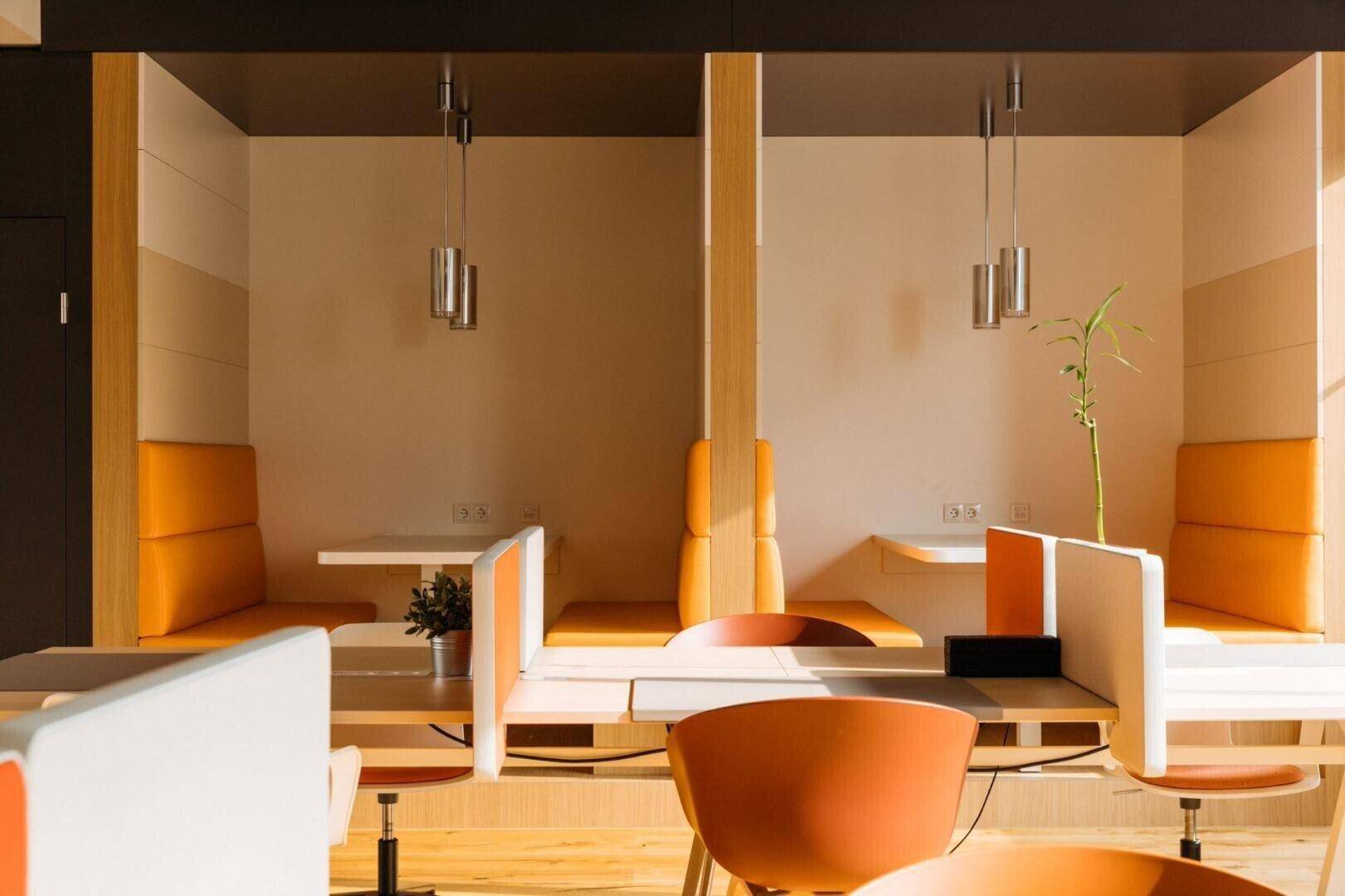 Moderne Arbeitskabinen mit orangefarbenen Polstern, Holzboden und indirekter Beleuchtung.