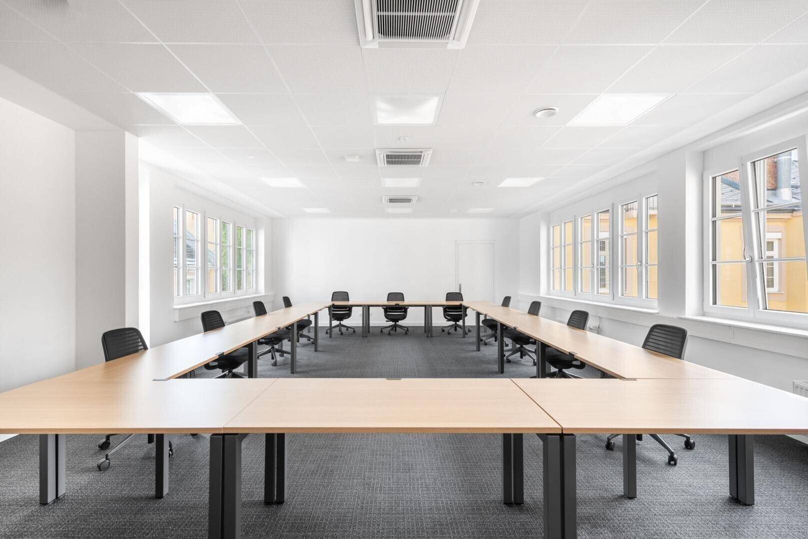 Großer Konferenzraum mit U-förmiger Tischordnung, Teppichboden und vielen Fenstern für helle Besprechungen.