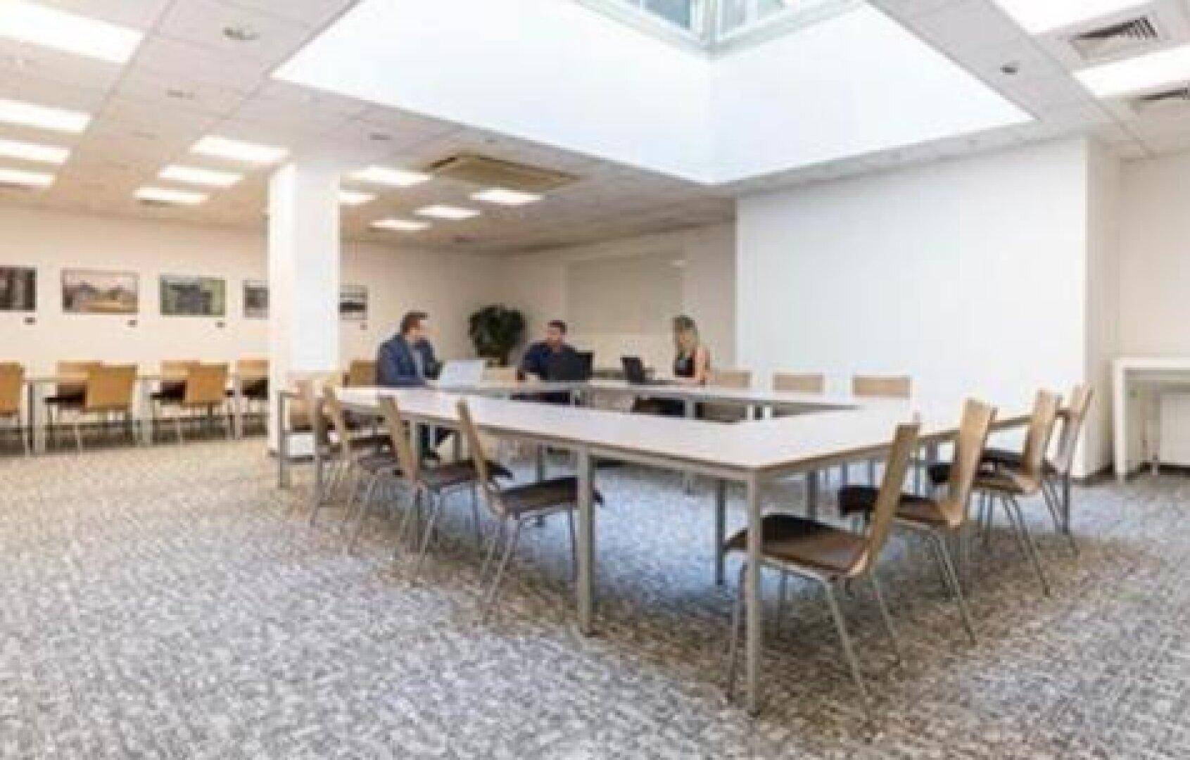 Großer Konferenzraum mit U-förmigem Tisch, Teppichboden und Oberlicht für viel natürliches Licht.
