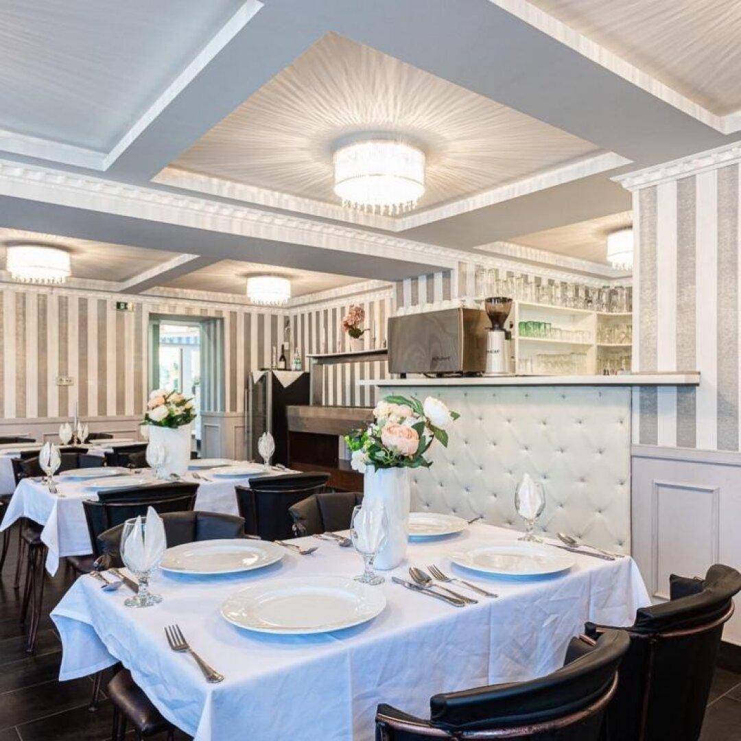 Stilvoller Restaurantbereich mit gestreiften Tapeten, eleganten Tischen und einer kleinen Bar.