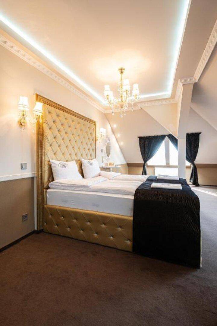 Elegantes Schlafzimmer im Dachgeschoss mit einem großen Bett, Kronleuchter und indirekter Beleuchtung.