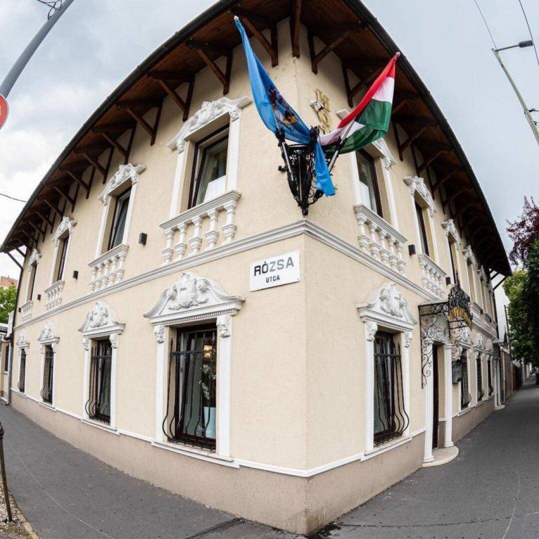Eckansicht eines historischen Gebäudes mit Stuckfassade, Fenstern und Straßenschildern.