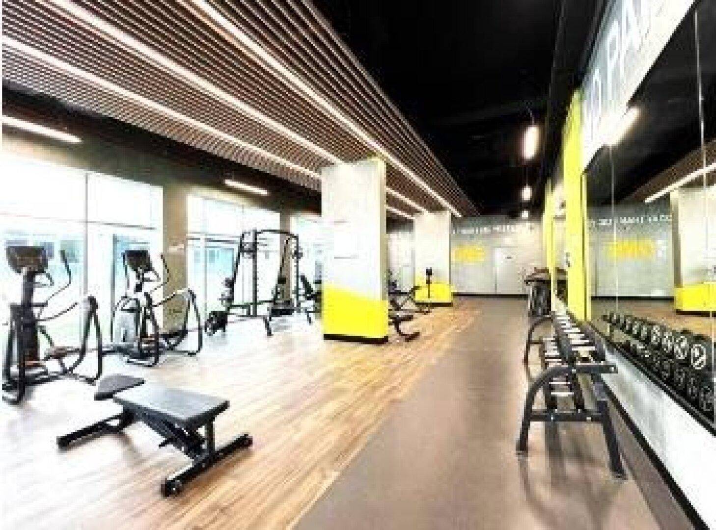 Moderner Fitnessraum mit vielfältigen Trainingsgeräten und großen Spiegeln.