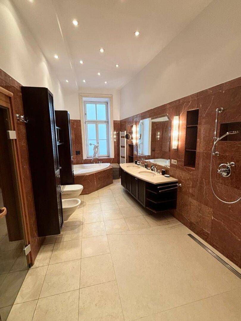 Luxuriöses Badezimmer mit roten Marmorfliesen, Doppelwaschbecken und Badewanne.