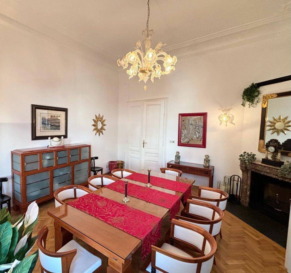Klassisches Esszimmer mit großem Holztisch, Kronleuchter und Kamin.