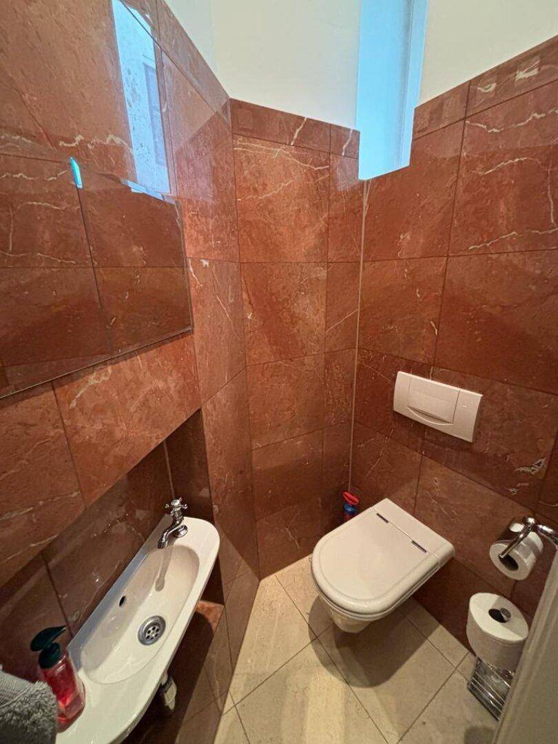 Modernes Gäste-WC mit roten Marmorfliesen und wandhängendem WC.