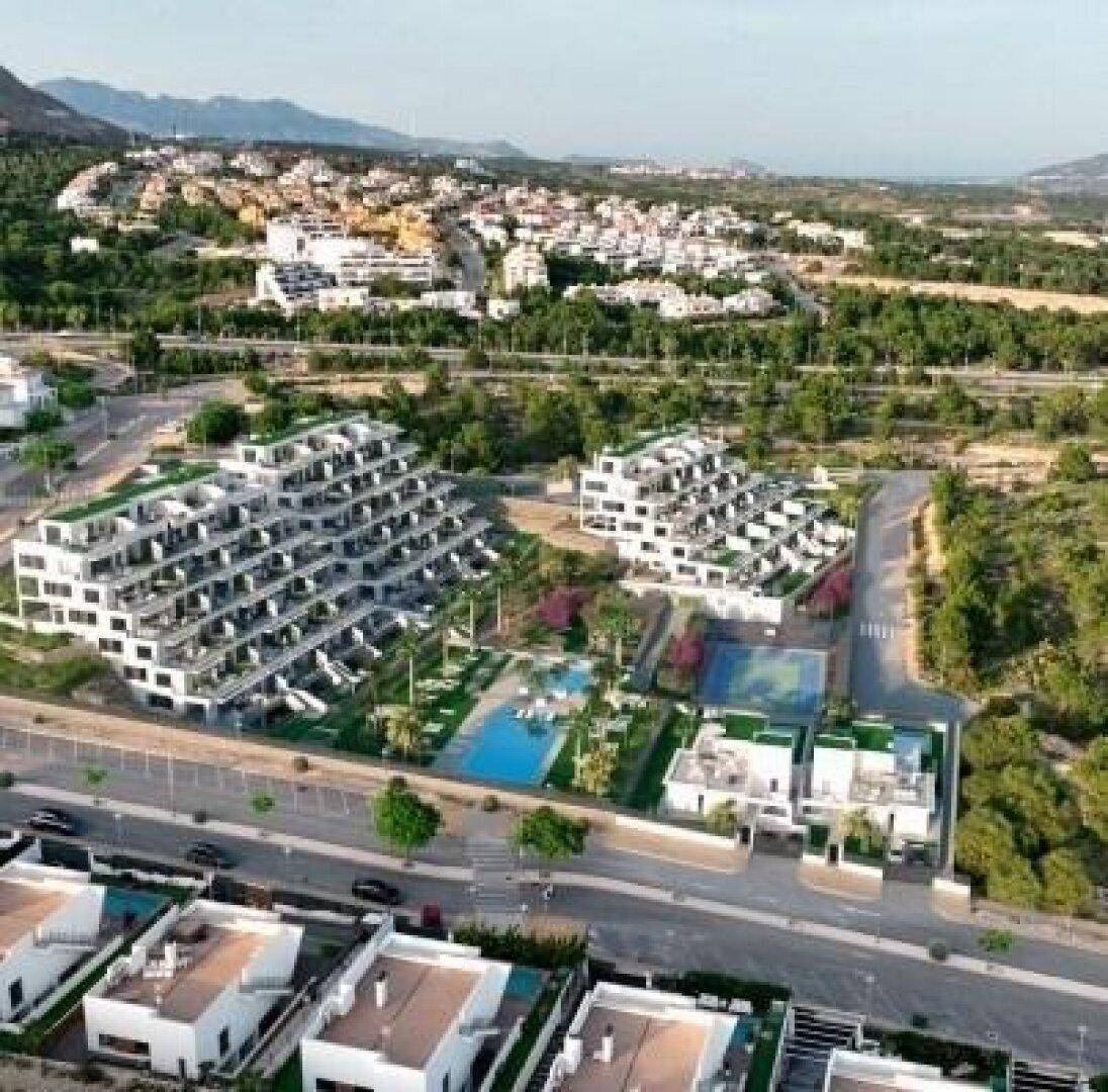 Luftaufnahme einer modernen Wohnanlage mit Pools, Tennisplatz und Bergblick in grüner Umgebung.