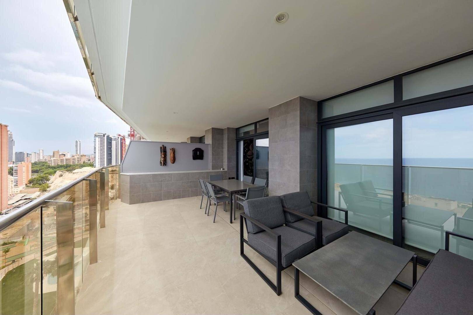 Große Terrasse mit Lounge-Möbeln und Panoramablick auf die Stadt und das Meer.