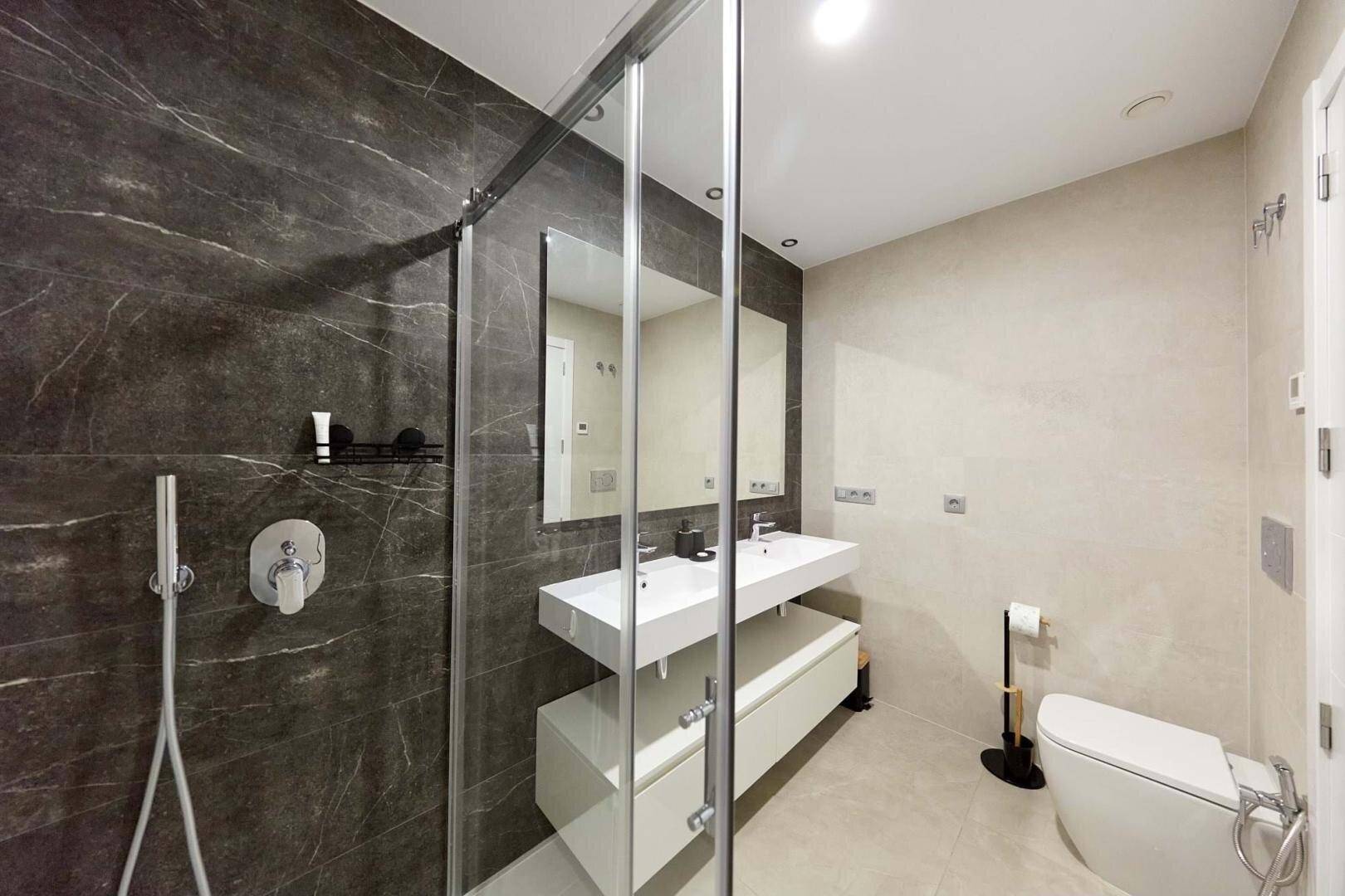 Elegantes Badezimmer mit begehbarer Dusche, Doppelwaschbecken und Wand-WC.