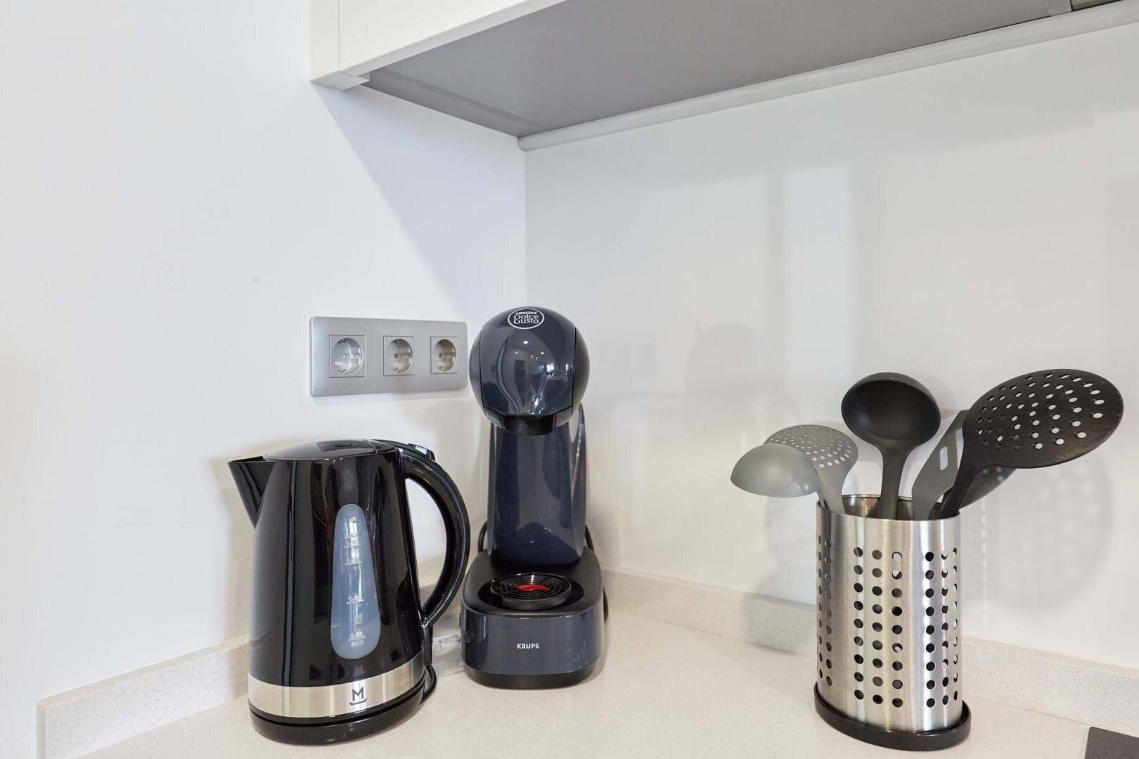 Küchenarbeitsplatte mit Kaffeemaschine, Wasserkocher und Küchenutensilien.