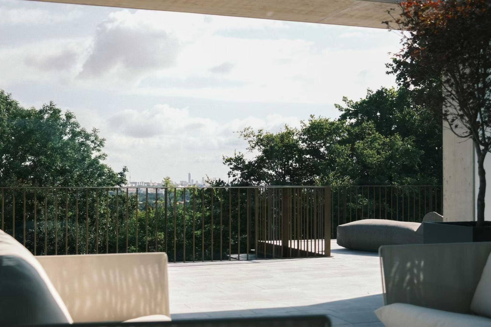 Geräumige Terrasse mit Loungemöbeln und weitem Blick über die Baumwipfel bis zur Stadt.