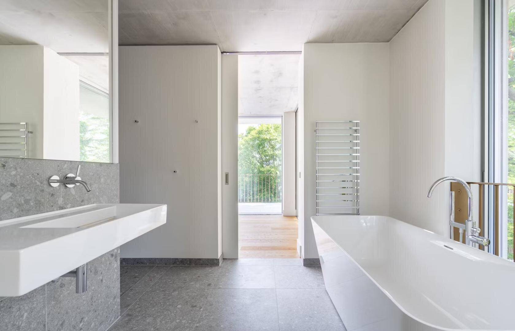 Modernes Badezimmer mit freistehender Badewanne, Einzelwaschbecken und Zugang zum Balkon.