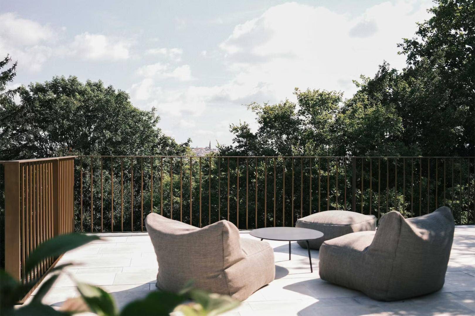Gemütliche Terrasse mit Sitzsäcken und einem Tisch, umgeben von viel Grün und Weitblick.
