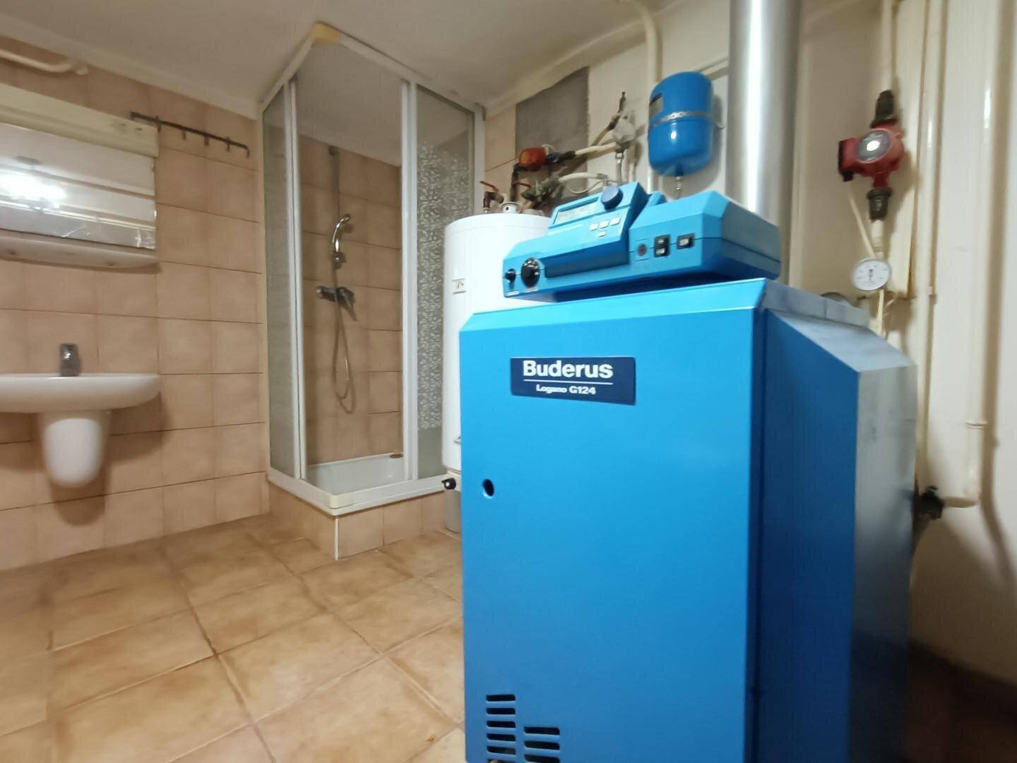 Hauswirtschaftsraum mit Heizkessel, Duschkabine und Waschbecken.