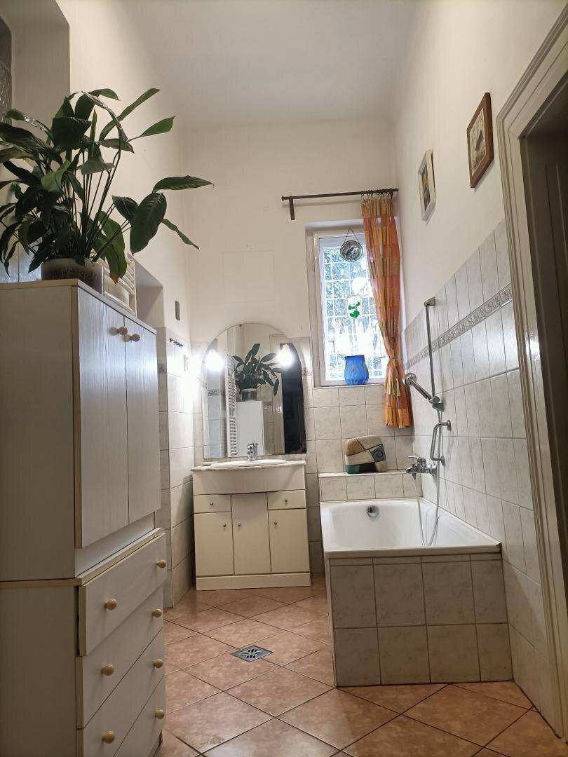 Helles Badezimmer mit Badewanne, Waschbecken und Fliesenboden.