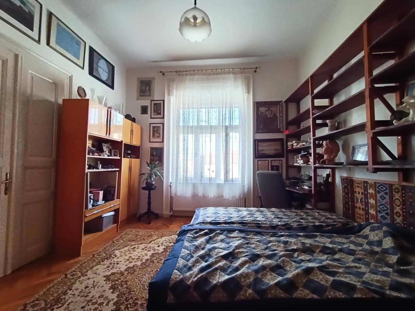 Gemütliches Schlafzimmer mit zwei Betten, Holzregalen und Parkettboden.