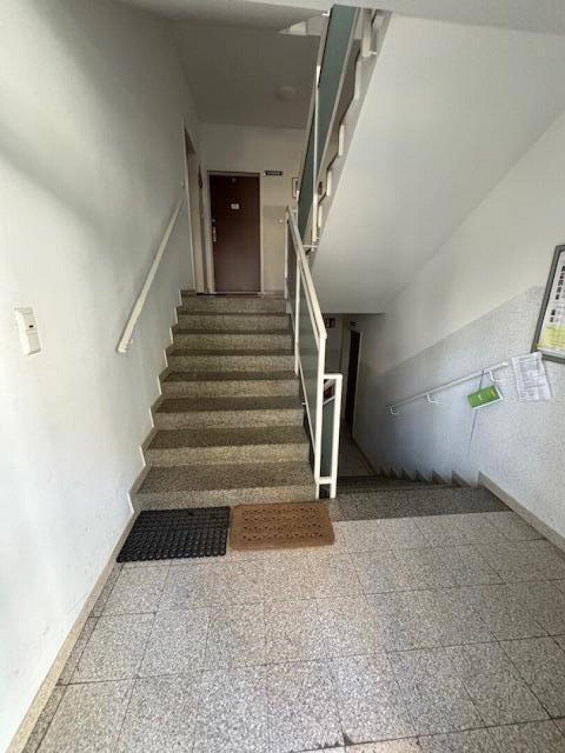 Treppenhaus im Mehrfamilienhaus mit Fliesenboden und Geländer.