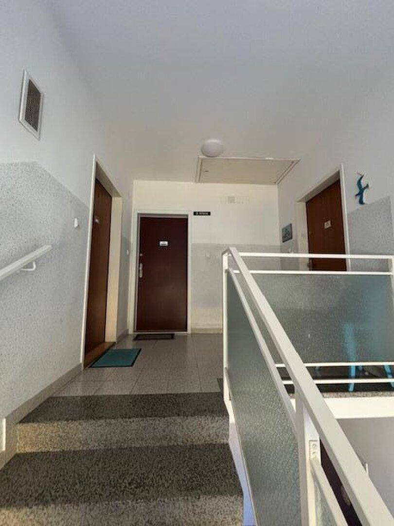 Treppenhaus und Flur im Mehrfamilienhaus mit Zugang zu den Wohnungen.