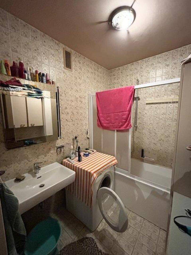 Badezimmer mit Badewanne, Duschvorrichtung, Waschbecken und Waschmaschine.