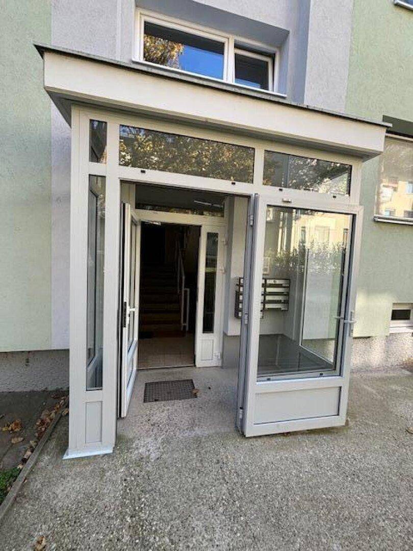 Eingangsbereich des Mehrfamilienhauses mit Glasportal und Briefkästen.