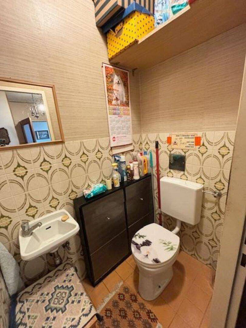 Kleines Gäste-WC mit WC, Waschbecken und gemusterten Fliesen.
