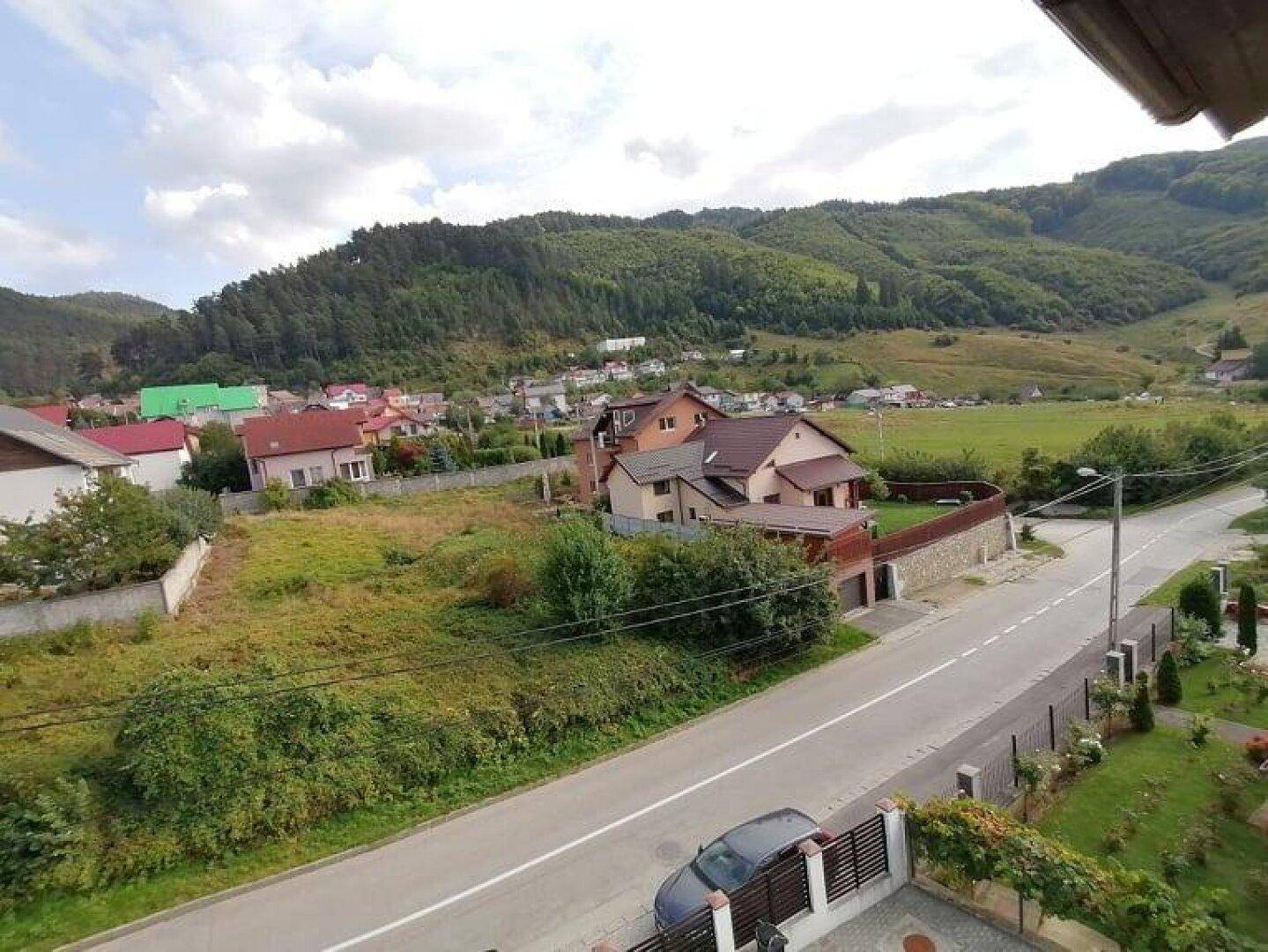 Weitläufige Aussicht auf eine ländliche Gegend mit Häusern, Hügeln und viel Grün.