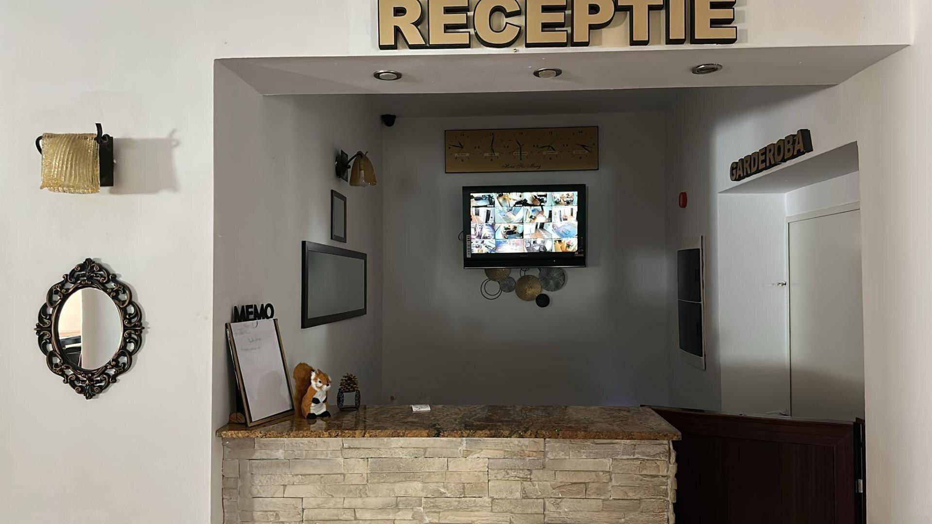 Empfangsbereich mit Steintheke, Wandfernseher und dekorativen Elementen.