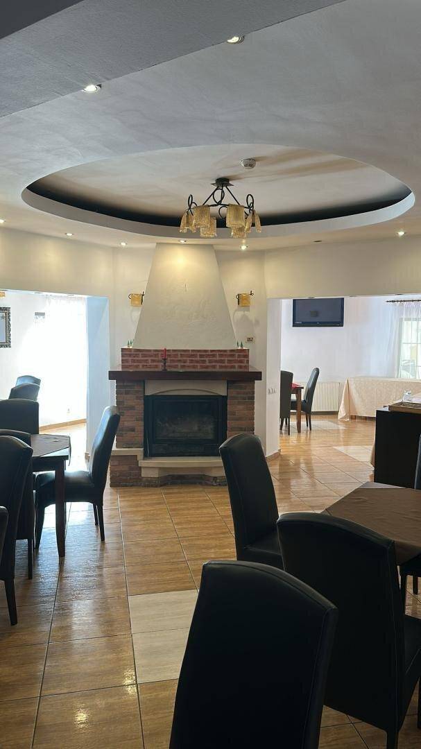 Geräumiger Speisesaal mit Kamin, dunklen Stühlen und einem dekorativen Deckenelement.