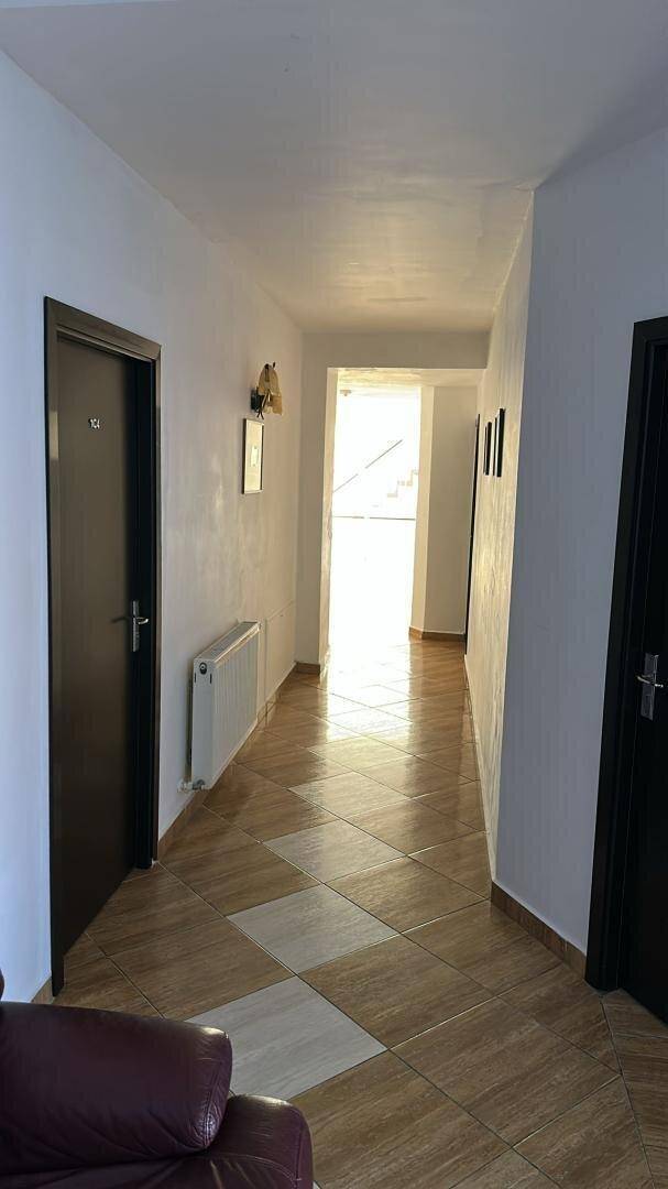 Heller Flur mit Fliesenboden, Heizkörper und dunklen Türen.