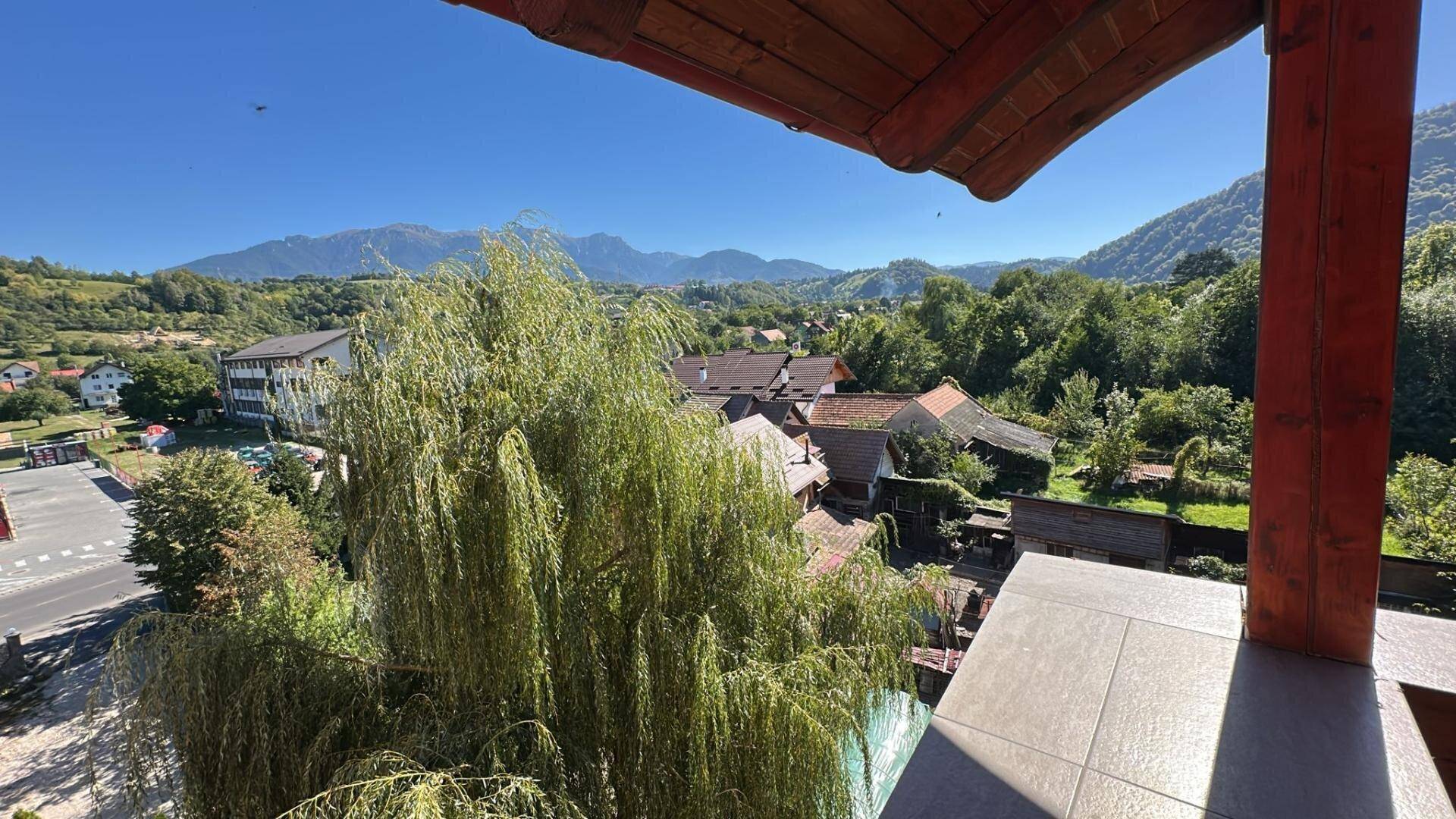 Aussicht von einem Balkon auf eine grüne Landschaft mit Bergen und Häusern.