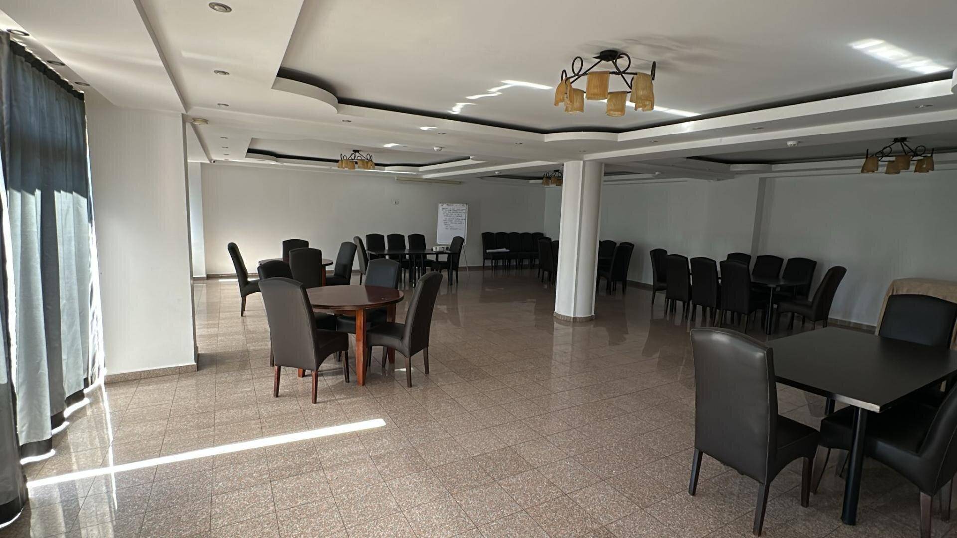 Großer Konferenzraum oder Veranstaltungsbereich mit flexiblen Sitzordnungen und viel Tageslicht.
