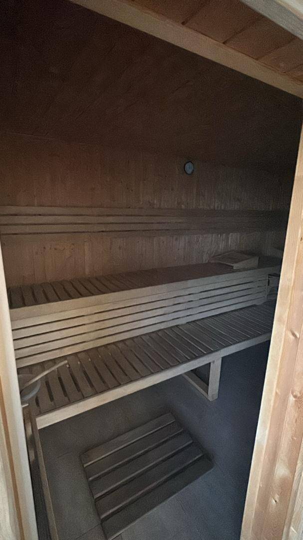 Traditionelle Holzsauna mit mehreren Bänken und dunklem Boden.