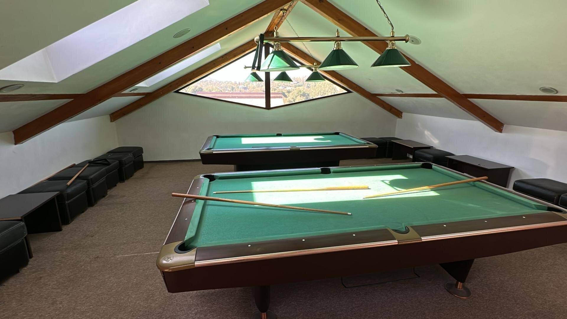 Dachgeschoss-Spielzimmer mit Billardtischen, Holzbalken und Dachfenstern.
