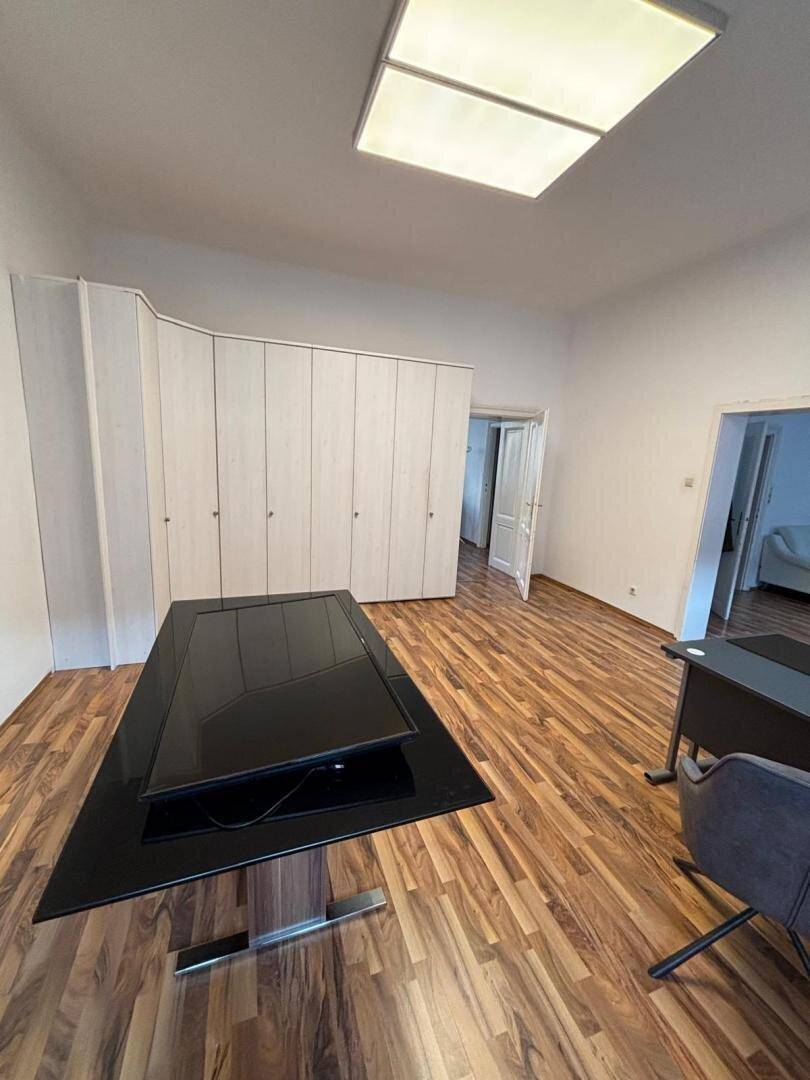 Büro mit Holzboden, Einbauschränken und einem modernen Schreibtisch in der Mitte des Raumes.