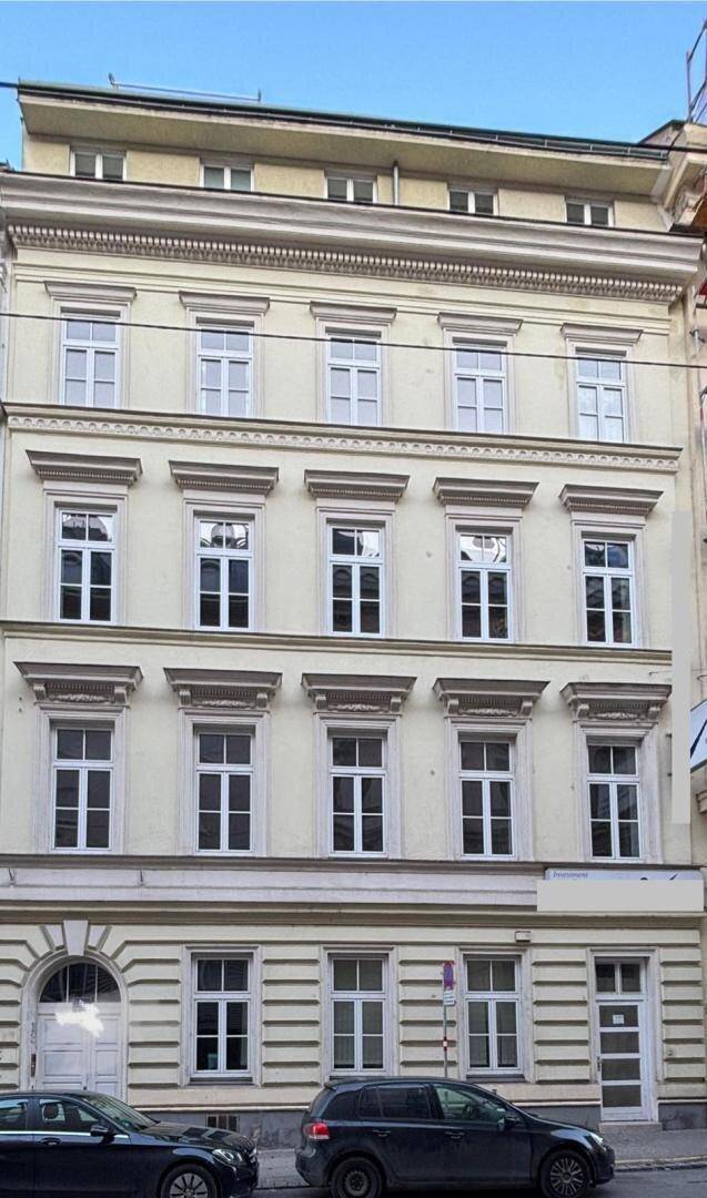 Historisches Gebäude mit einer hellen Fassade, vielen Fenstern und traditionellen Verzierungen.