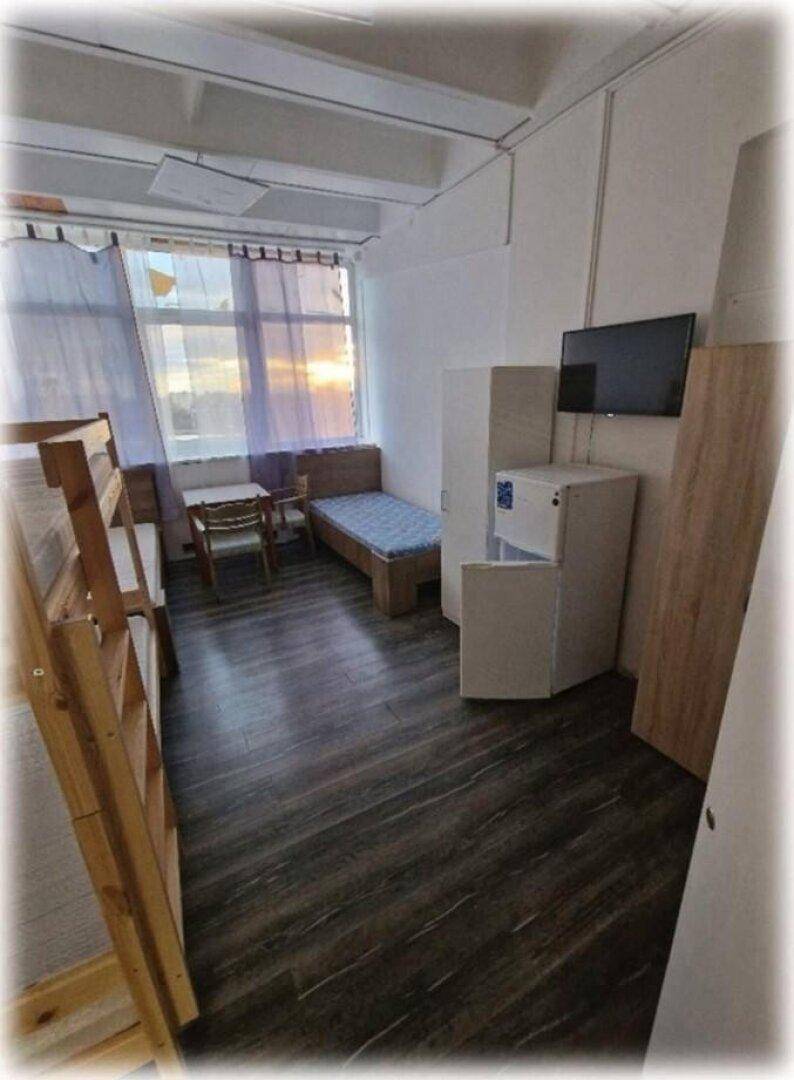 Helles Schlafzimmer mit Etagenbett, Einzelbett, Schreibtisch und Fernseher, gut beleuchtet durch das Fenster.