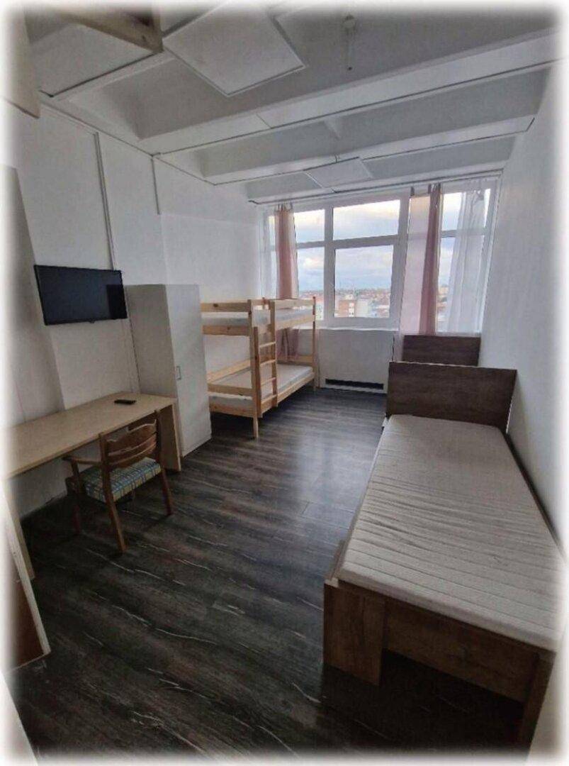 Geräumiges Schlafzimmer mit Etagenbett, Einzelbett, Schreibtisch und Fernseher, mit viel Tageslicht.