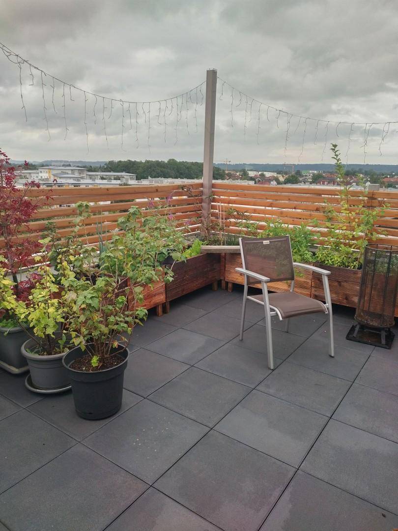 Geräumige Dachterrasse mit Hochbeeten, Holzzaun und weitem Blick über die Umgebung.