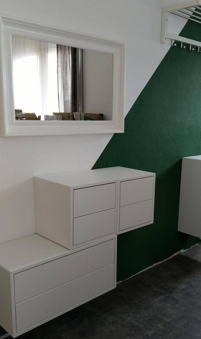 Moderner Flur mit schwebenden weißen Kommoden, Spiegel und einer grünen Akzentwand.