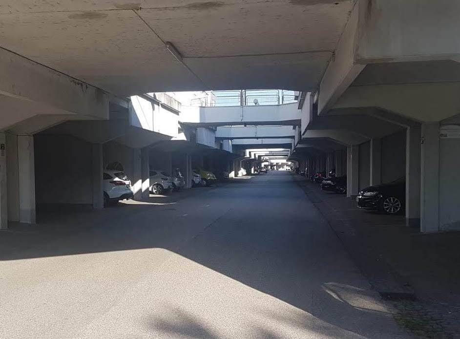 Überdachte Parkgarage mit zahlreichen Stellplätzen für Fahrzeuge unter einem Gebäude.