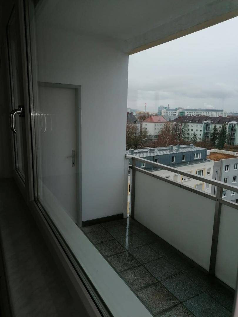 Kleiner Balkon mit Fliesenboden und Metallgeländer, bietet einen Blick auf die Stadt.