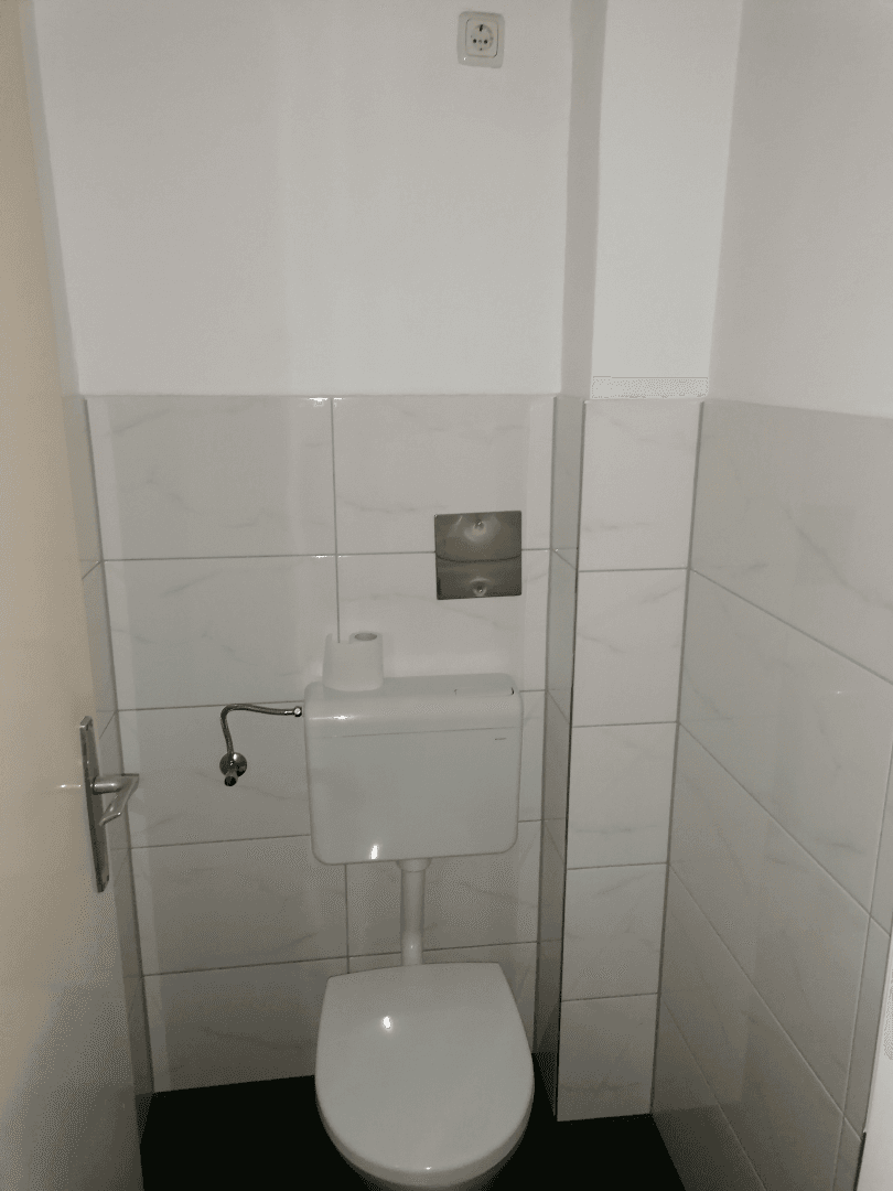 Sauberes WC mit Wandfliesen und einer modernen Toilette, ideal für Gäste.