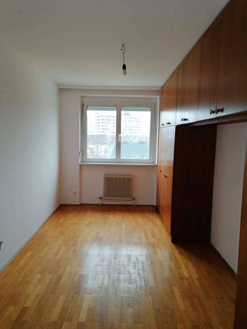 Langes Schlafzimmer mit Holzboden und eingebauten Holzschränken entlang einer Wand.