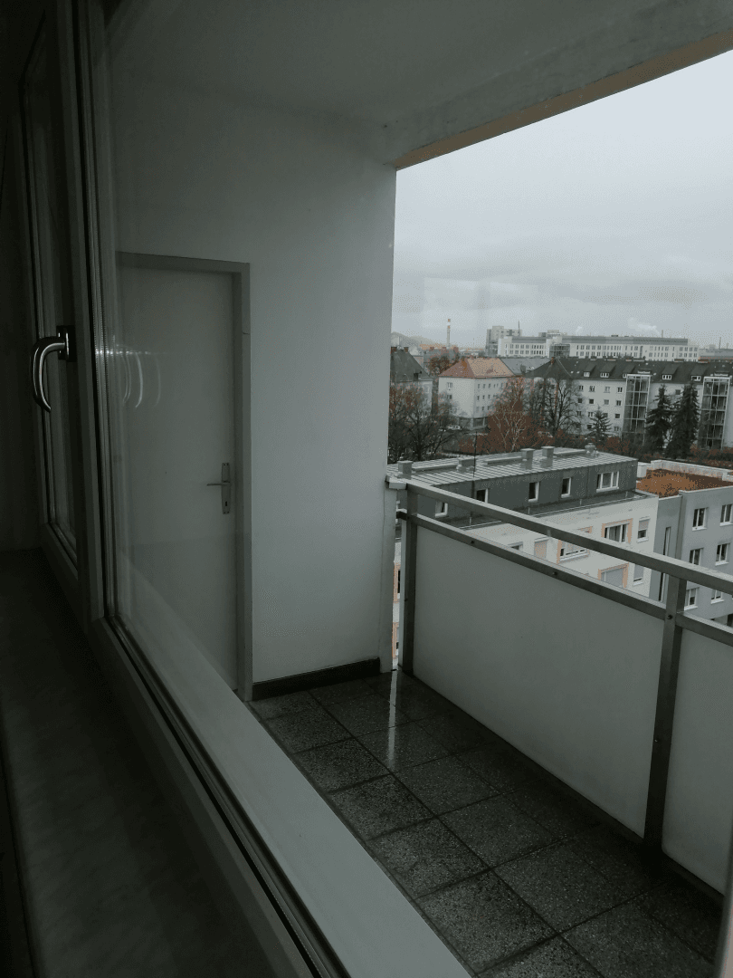 Kleiner Balkon mit Fliesenboden und Metallgeländer, bietet einen Blick auf die Stadt.