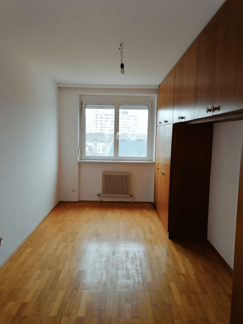Langes Schlafzimmer mit Holzboden und eingebauten Holzschränken entlang einer Wand.