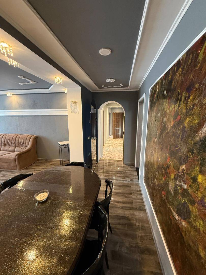 Offener Wohn- und Essbereich mit dunklem Boden und dekorativer Decke.