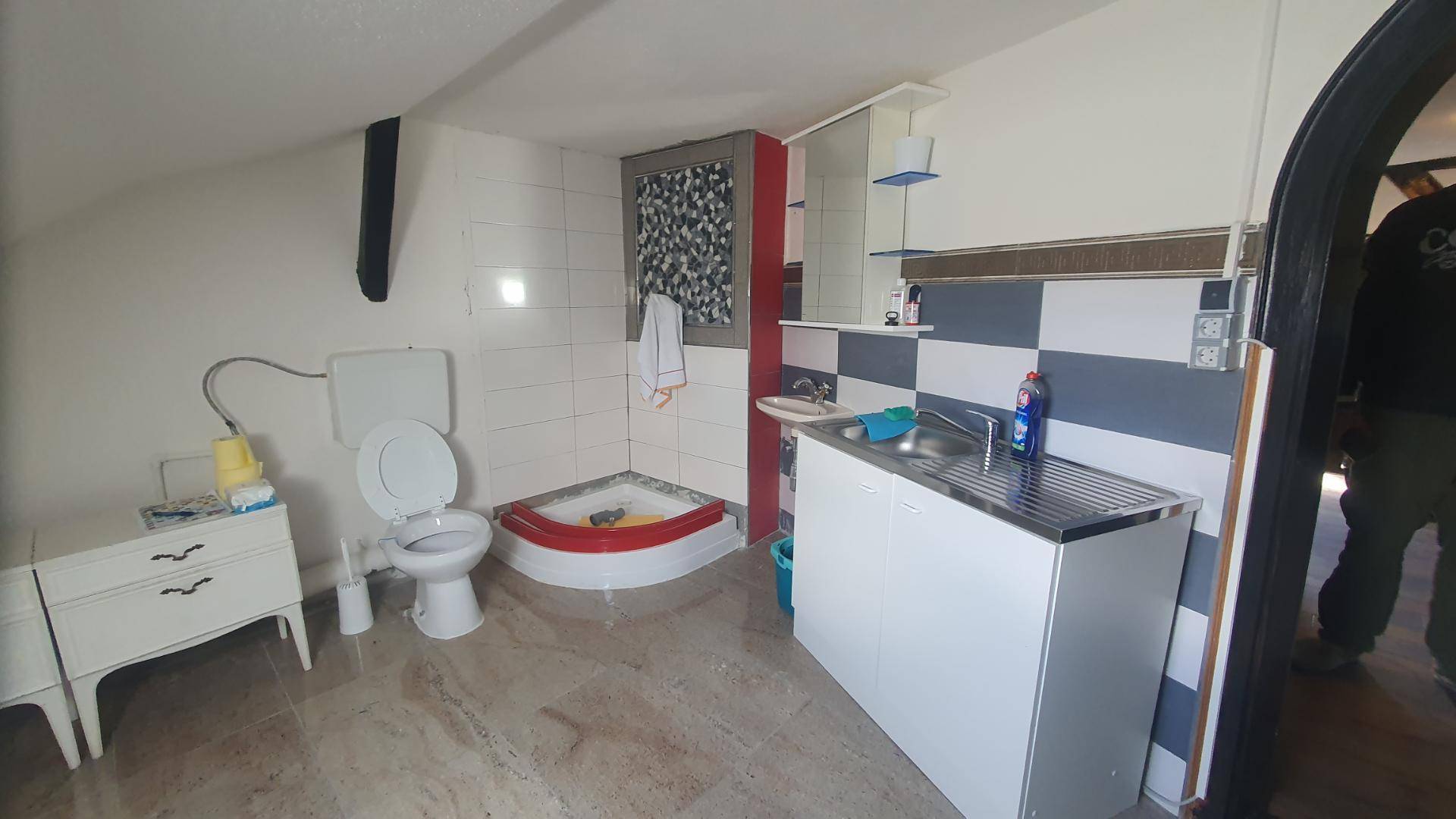 Kleines Badezimmer im Dachgeschoss mit Toilette, Dusche und Waschbecken.